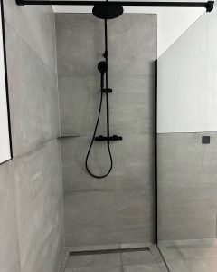 7:00 Uhr morgens in Hamburg-Winterhude. Der Wind drückt den Regen gegen die Fensterscheiben, und im Flur brennt noch das gedimmte Licht. Ich stehe in einem Badezimmer, das gerade seine Seele zurückbekommt. Der Boden ist offen, die alten Leitungen sind ersetzt, und der Laser wirft eine exakte Linie an die Wand. Hier entsteht gerade eine barrierefreie Dusche und Sitzbank.